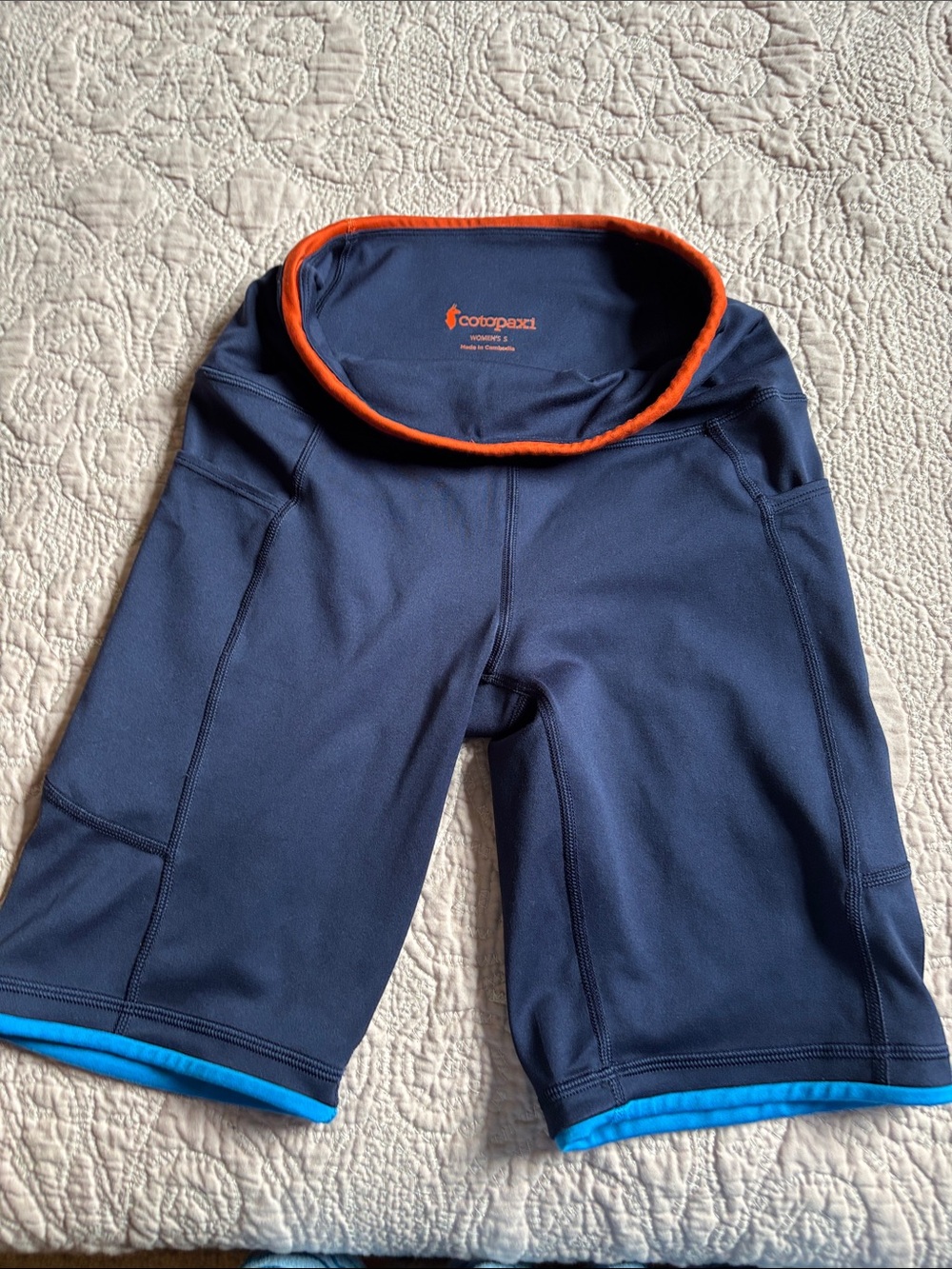 cotopaxi navy shorts with orange waistband and light blue hems